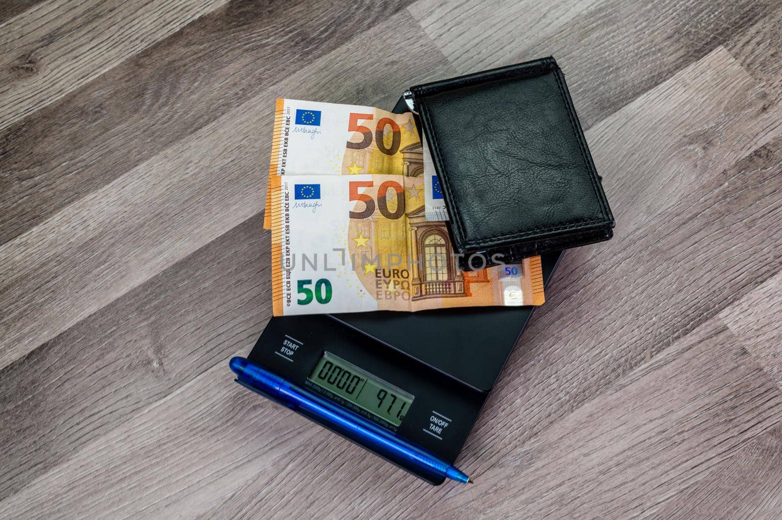 euro banknotes on top of a scale with portafolio on a wooden table