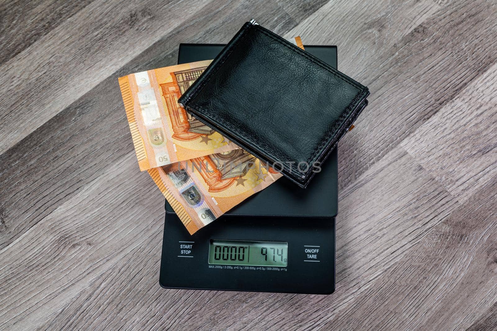 euro banknotes on top of a scale with portafolio on a wooden table