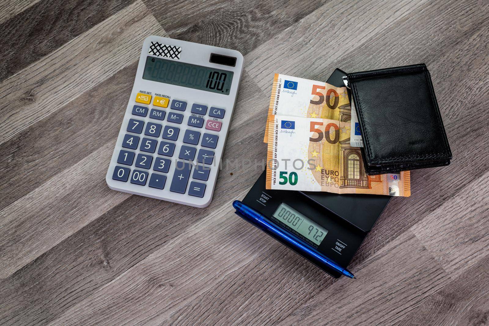 euro banknotes on top of a scale with nearby calculator by carfedeph