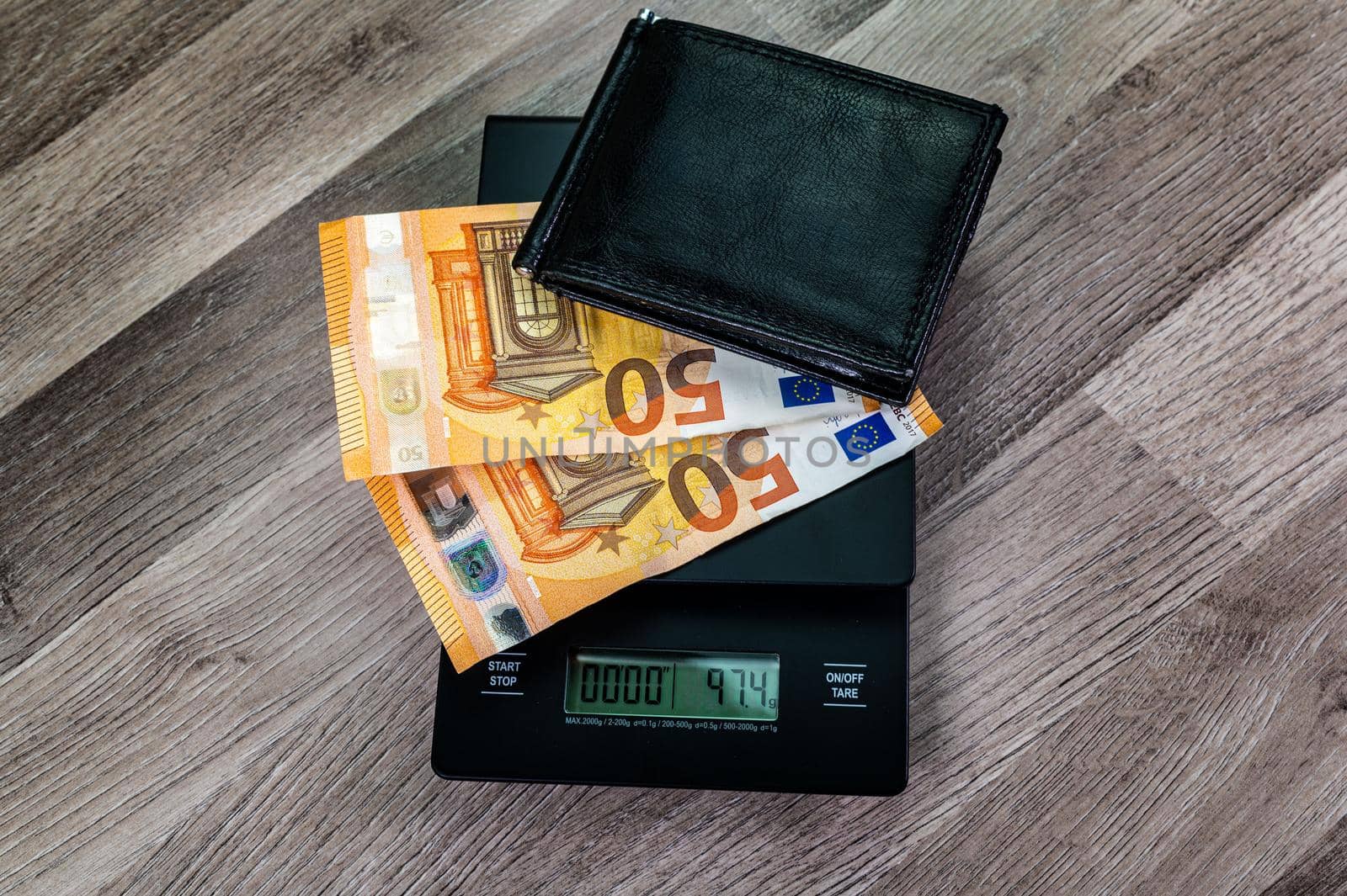 euro banknotes on top of a scale with portafolio on a wooden table