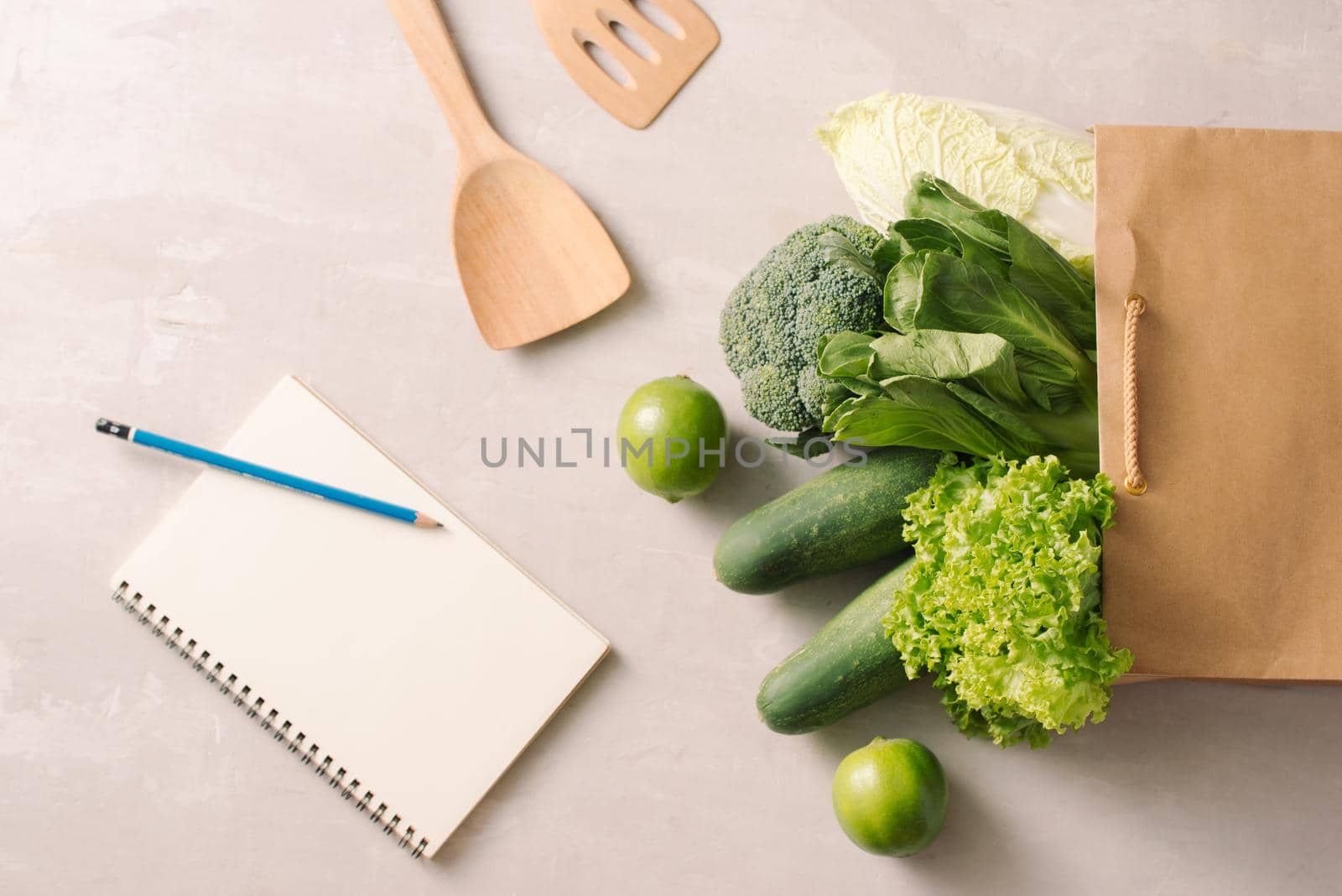 Paper bag full of healthy food with notepads on a gray background. Top view. Flat lay