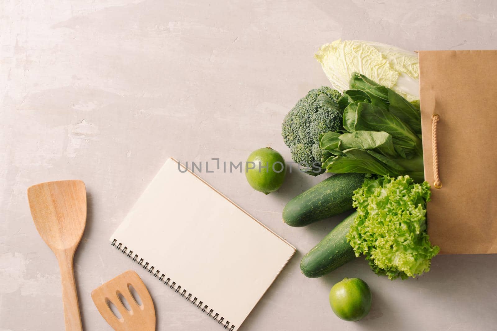 Paper bag full of healthy food with notepads on a gray background. Top view. Flat lay by makidotvn