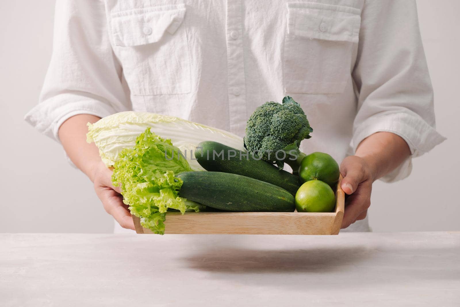 Market. Healthy vegan food. Fresh vegetables, berries, greens and fruits in wooden tray: cucumbers radish green peas ... white table. In man"s hands copy space