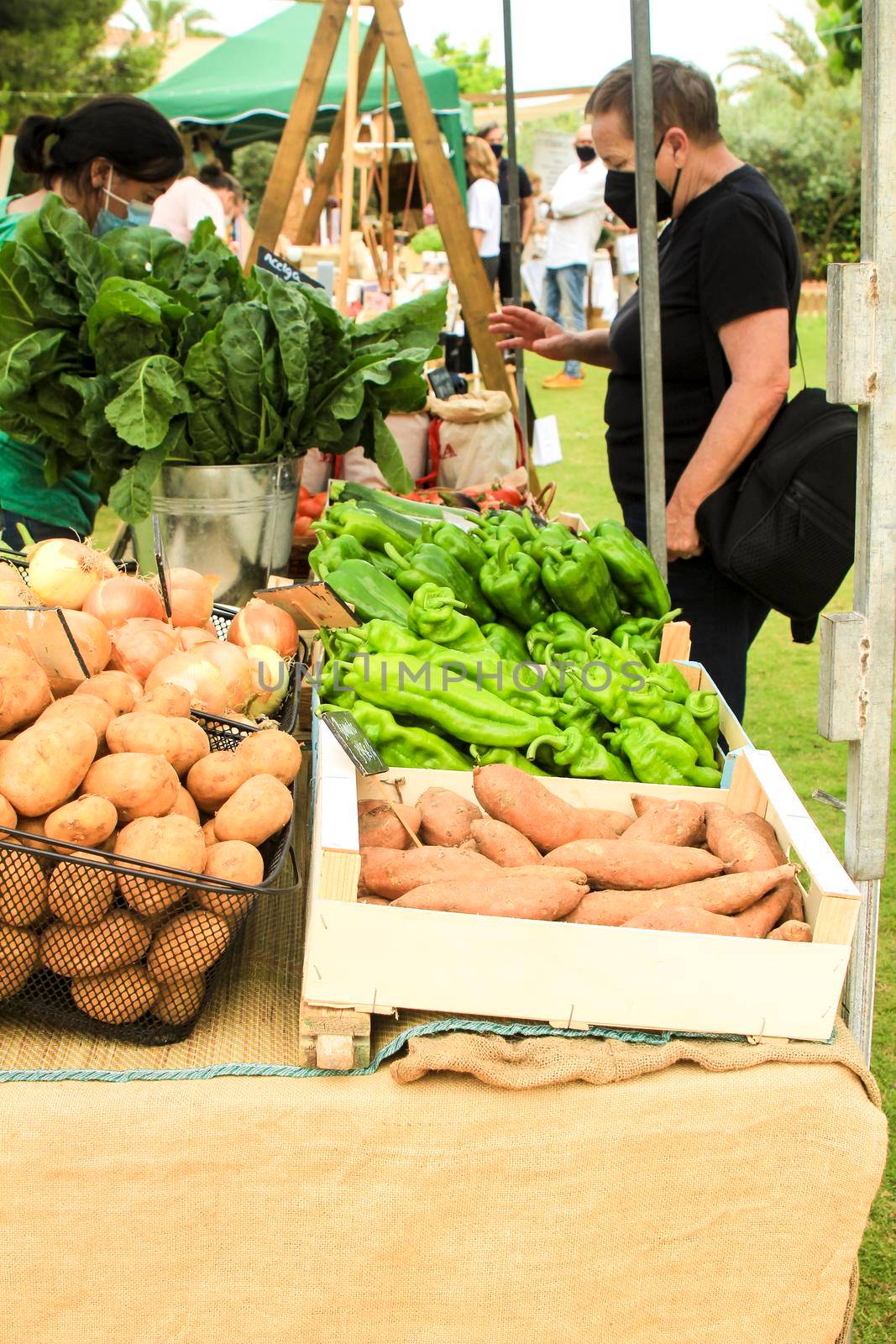 Elche, Alicante, Spain- June 20, 2021: People buying Fresh products for sale at an ecological and sustainable market held in the countryside of Elche