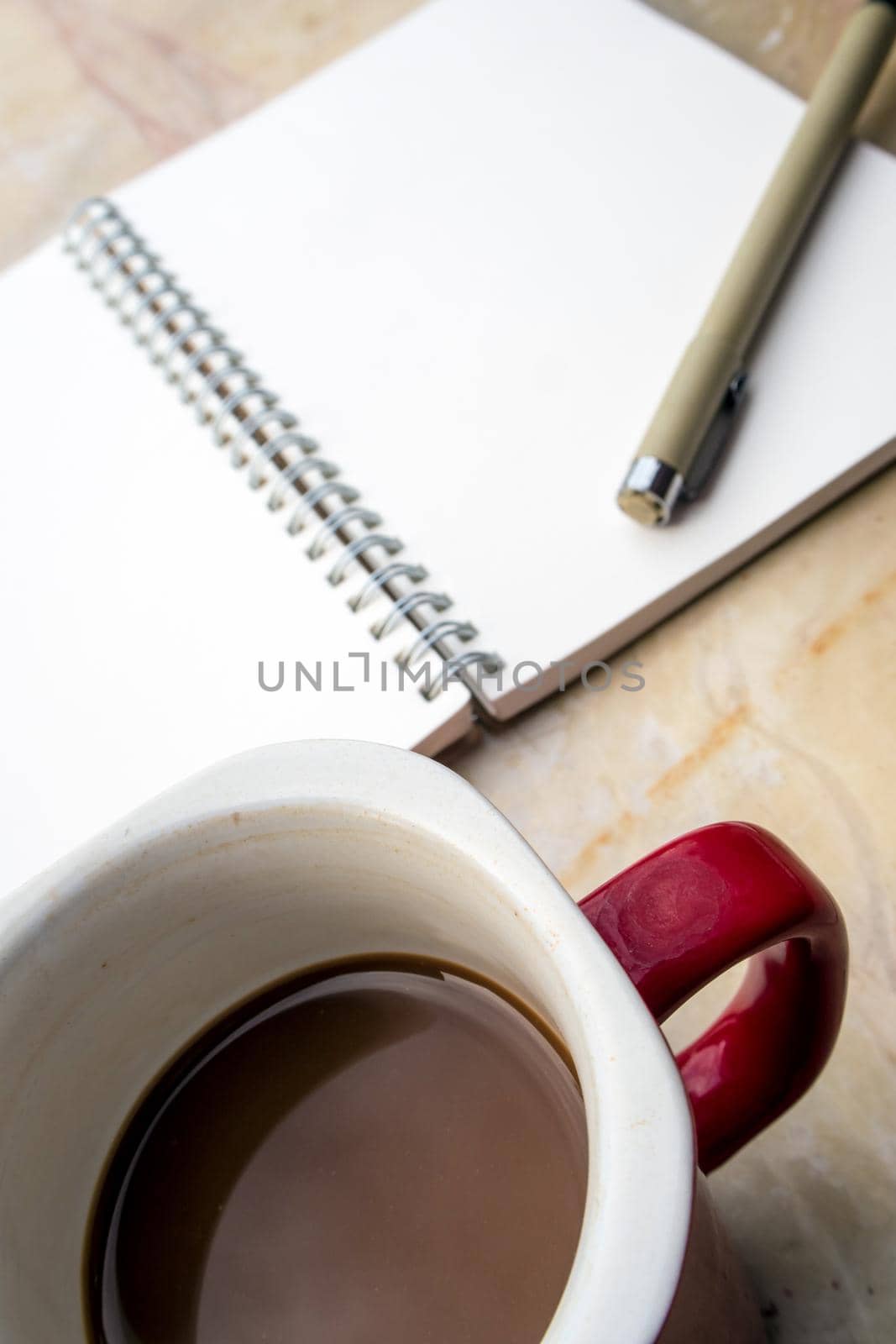 The blank page of a spiral notebook and coffee cup