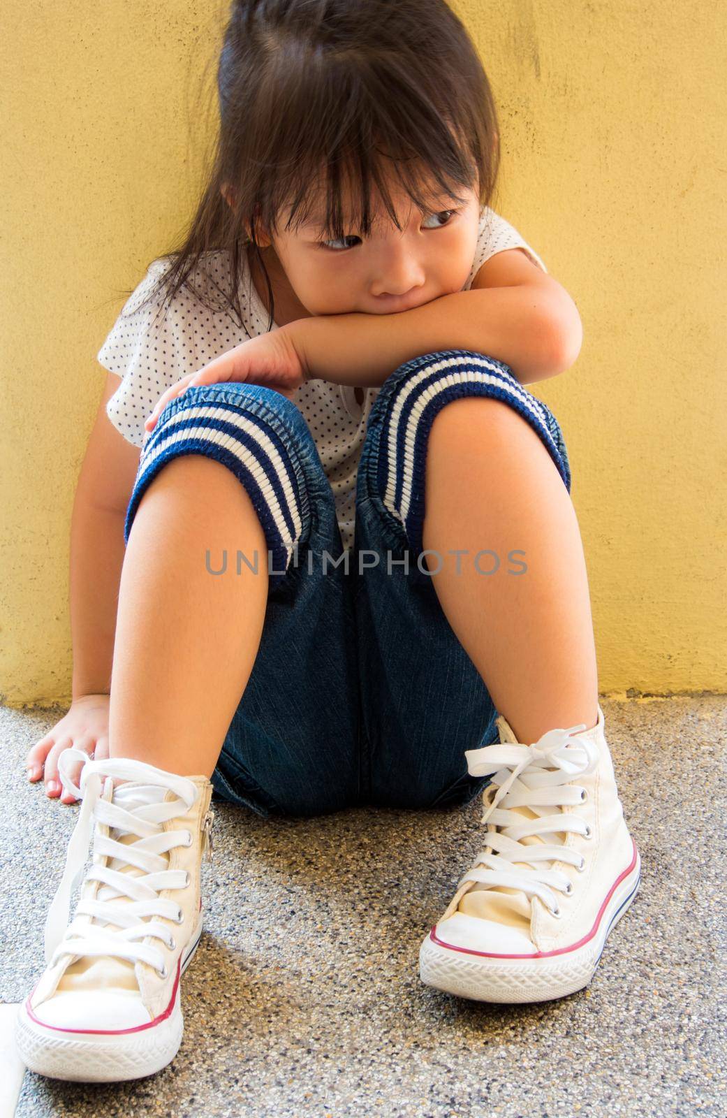 A Lonely girl sitting behind the concrete wall by Satakorn