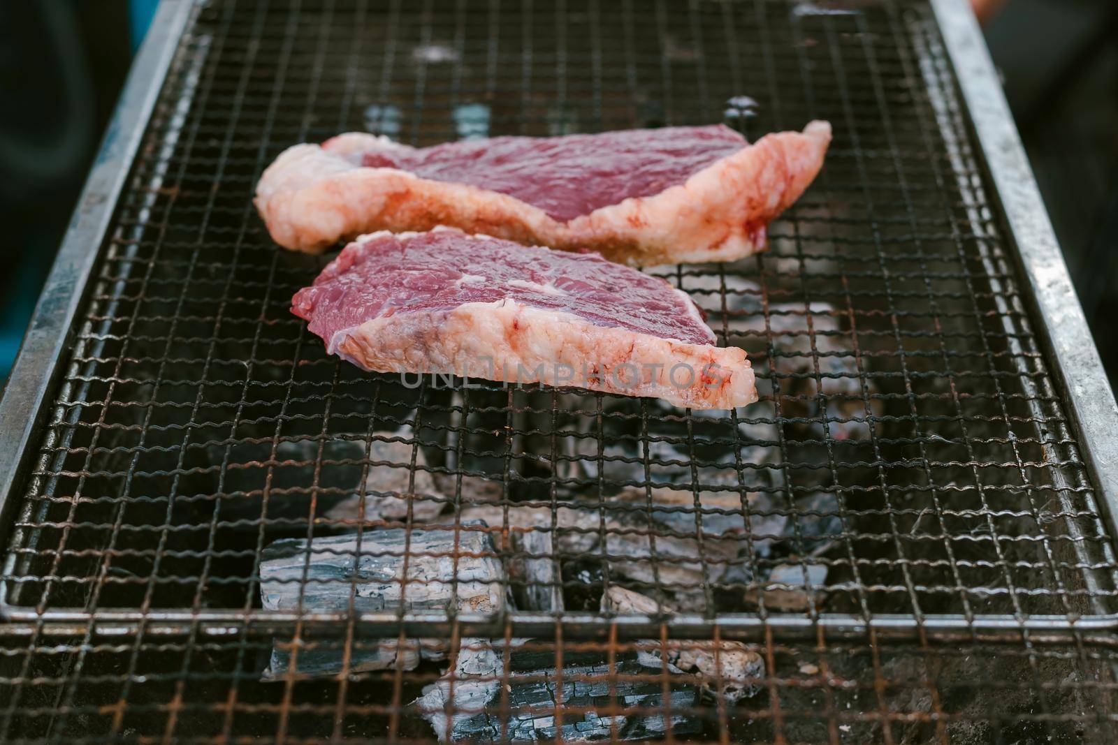 Grill the beef on the charcoal grill to cook steaks. by wattanaphob