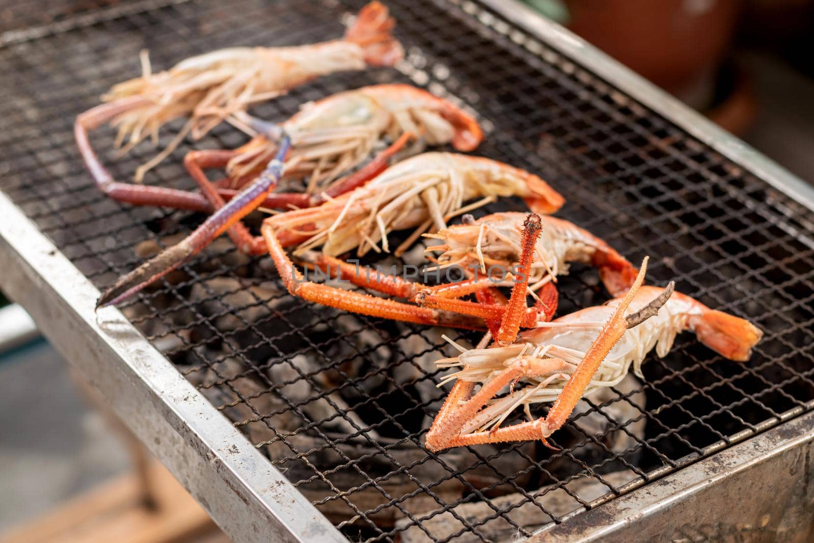 Some river prawns grilled on the iron rack over the charcoal. by wattanaphob