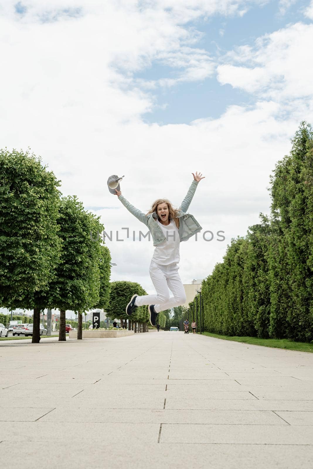 Happy young woman in white t-shirt jumping and screaming in the park. mock up design