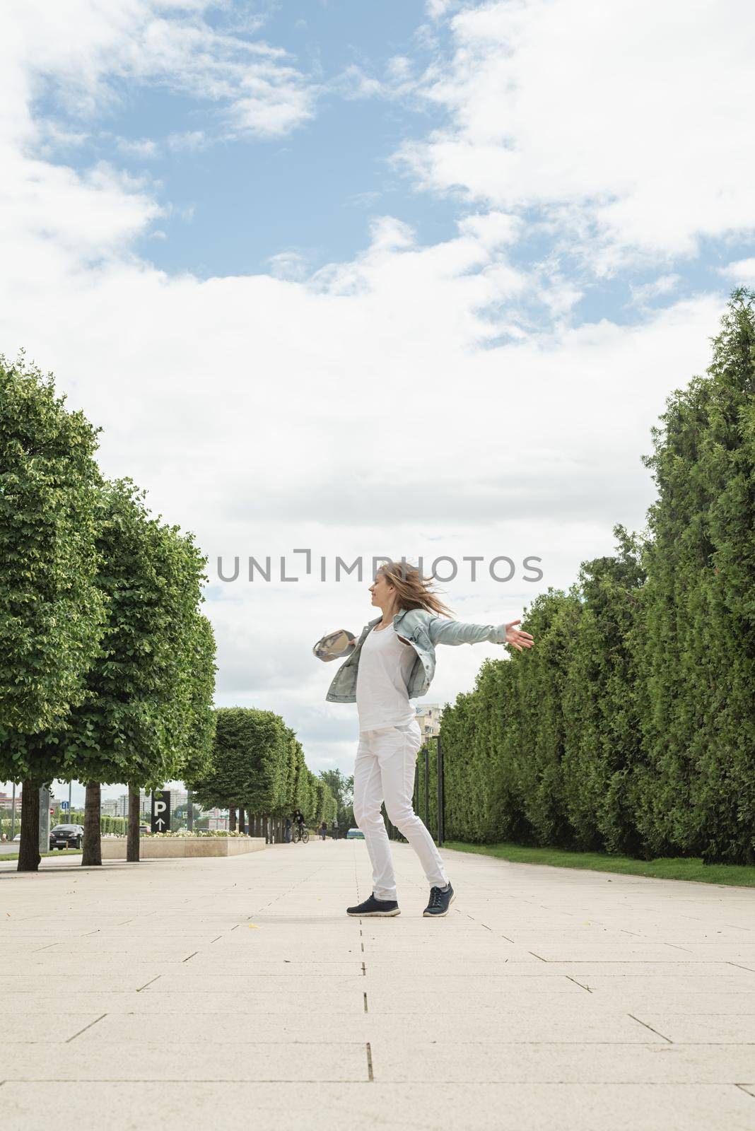 Beautiful young cheerful woman spinning around and dancing in a park. Happy woman having fun.