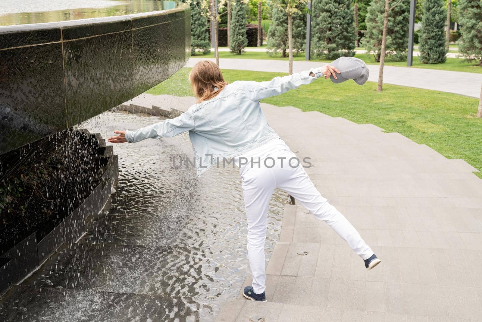 Woman standing by the fountain in the park by Desperada