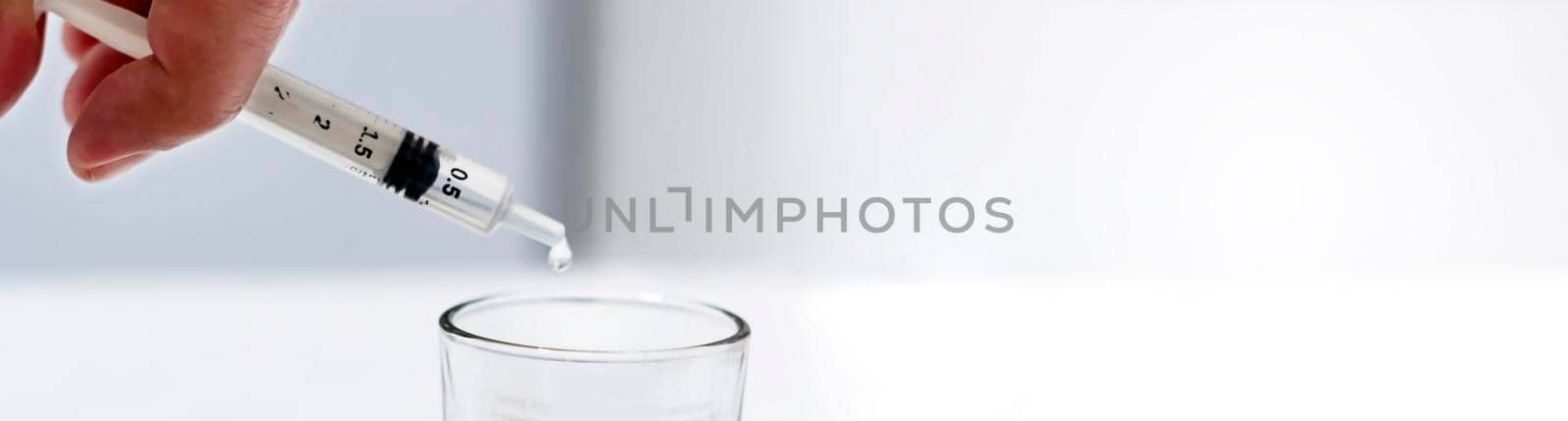 a researcher empties the liquid from a vial into a glass container to find a virus vaccine in a scientific analysis and research laboratory. Science and medical research