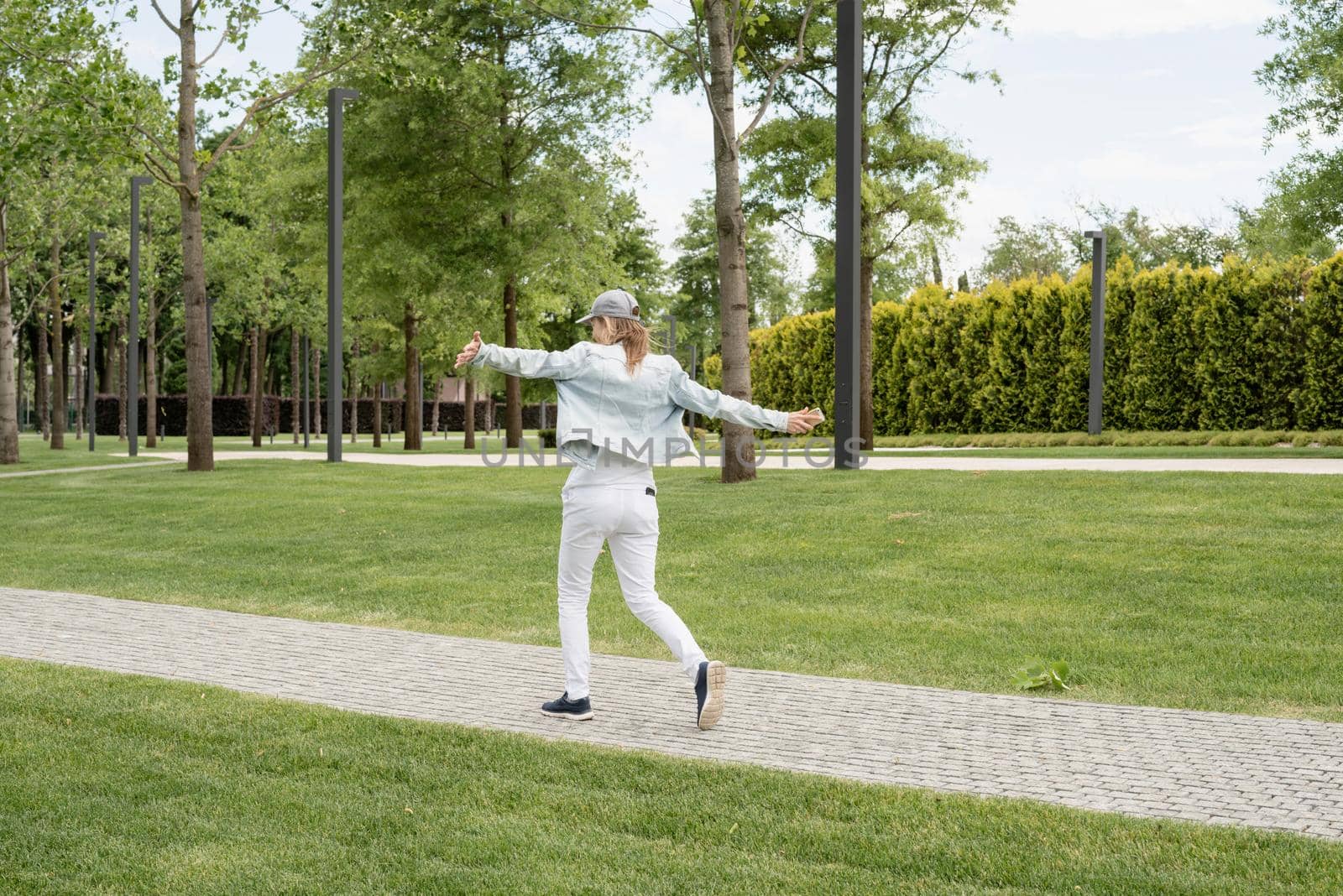 Woman in casual jeans clothes texting on her mobile phone, walking in the park