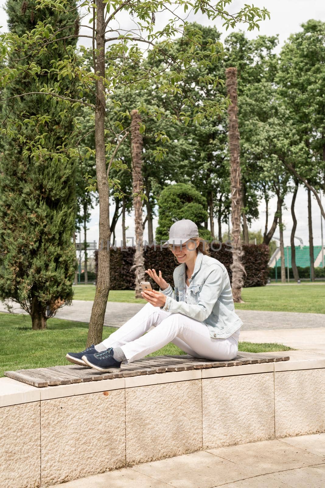 Woman sitting in the park outdoors taking selfie on her mobile phone