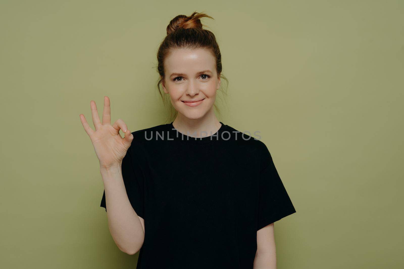 Calm brunette woman in black tee shirt showing okay sign by vkstock