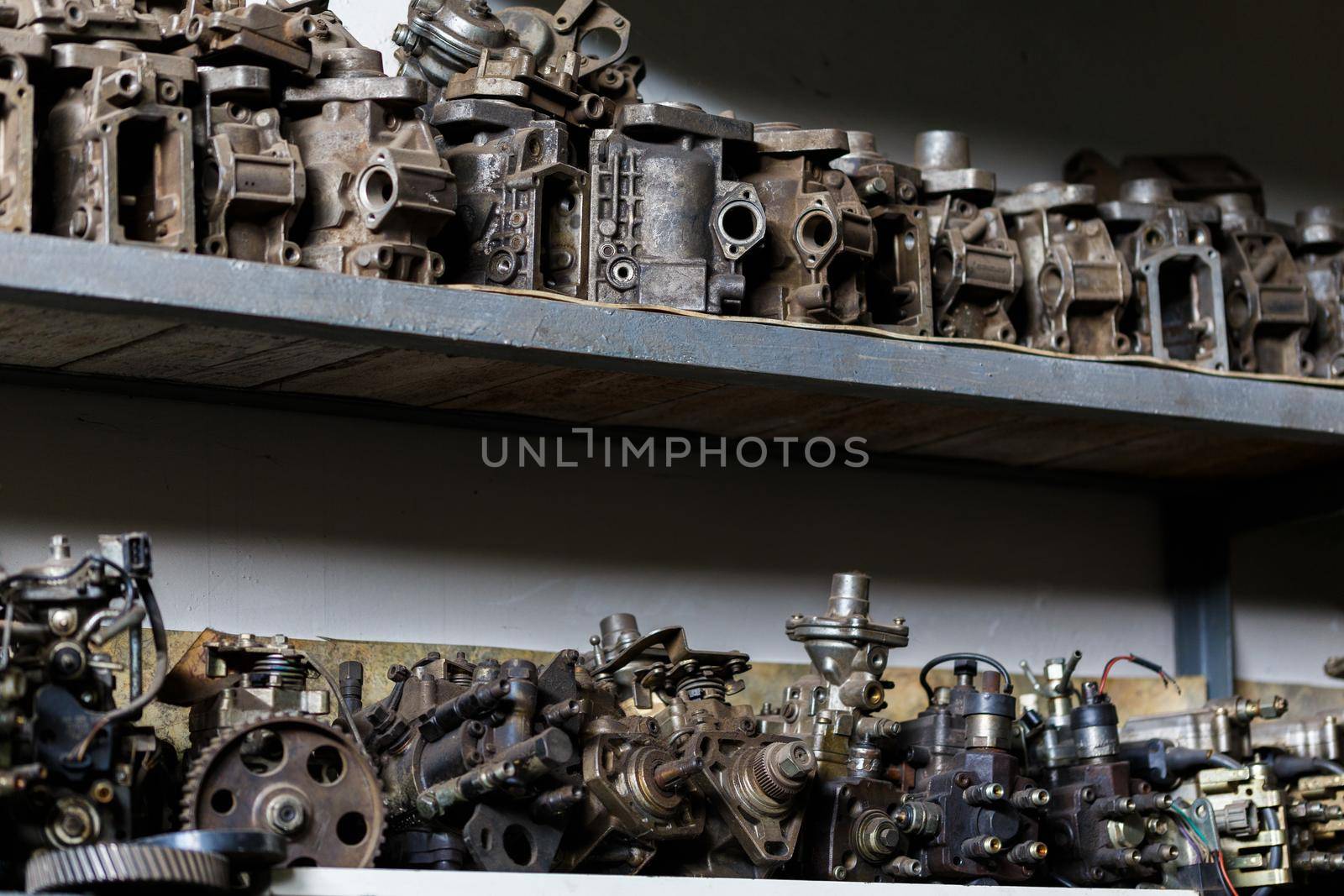 old dirty metal engine parts on dark garage shelf.