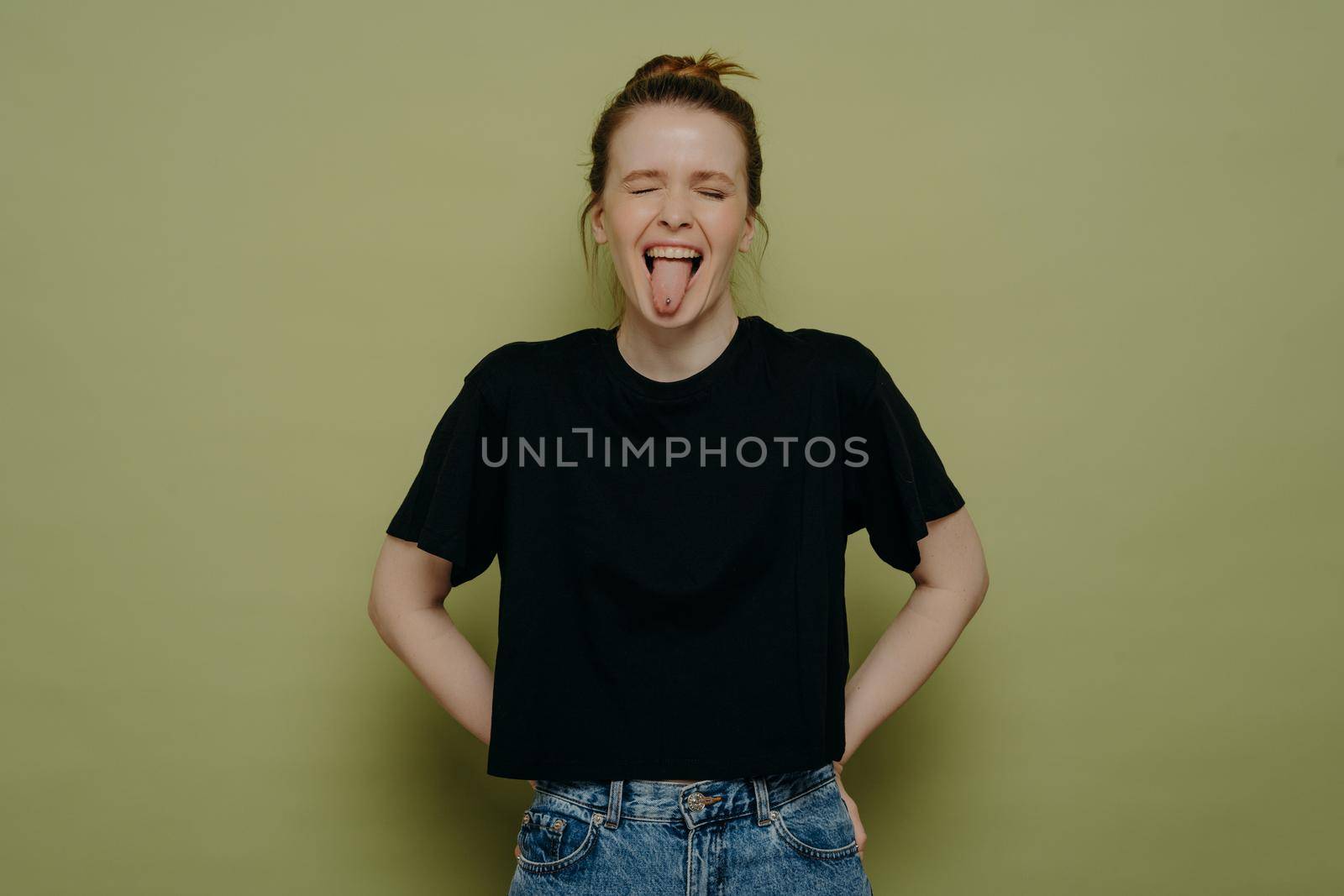 Silly brunette woman wearing casual clothes showing her tongue by vkstock