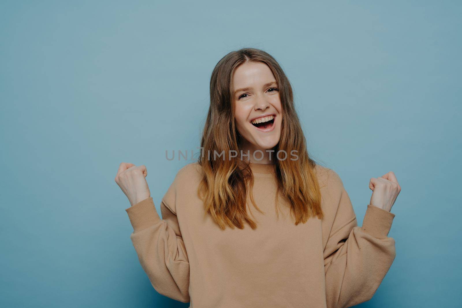 Teenage girl celebrating victory or success isolated on blue background by vkstock