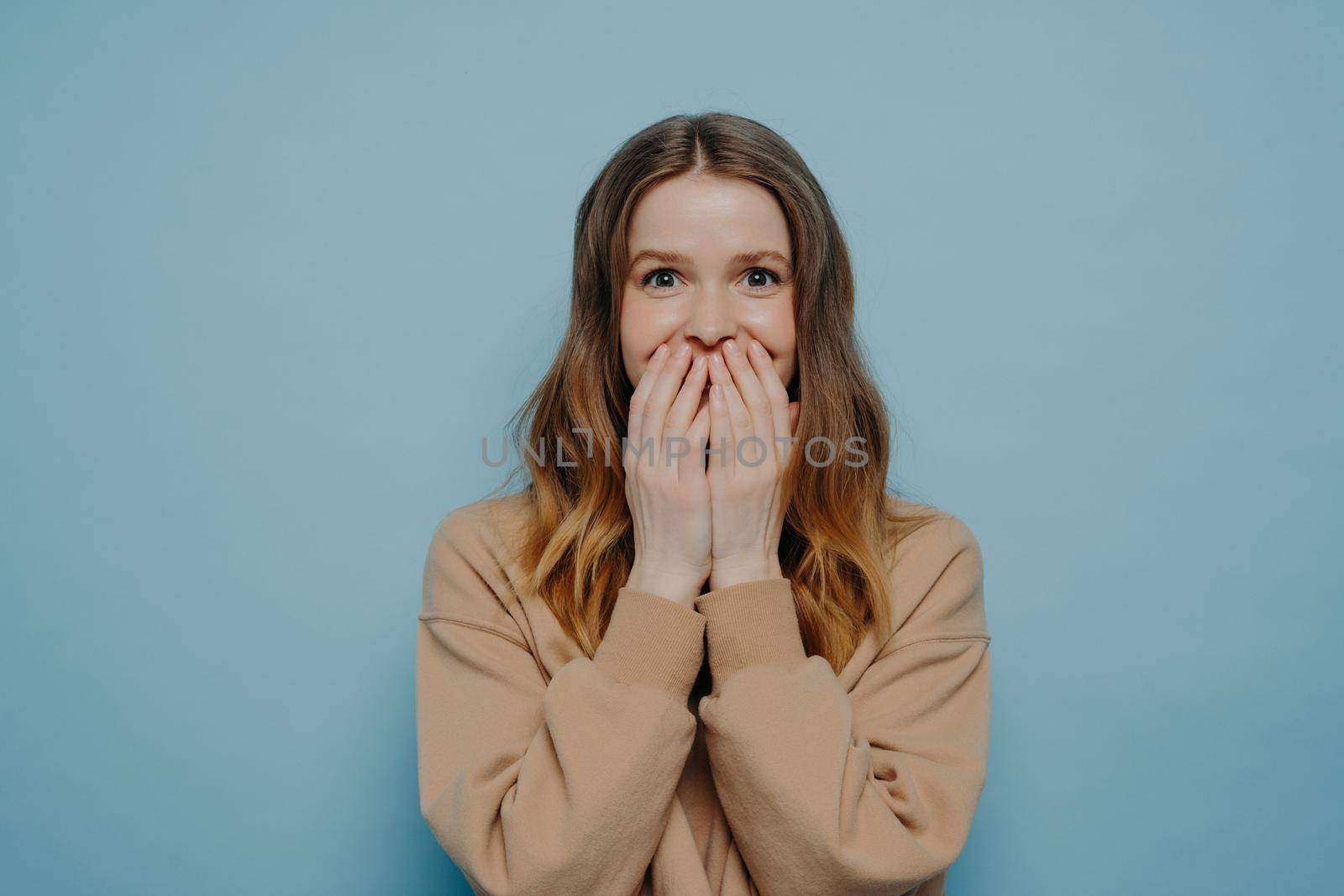 Young surprised teen girl in casual wear on blue background by vkstock