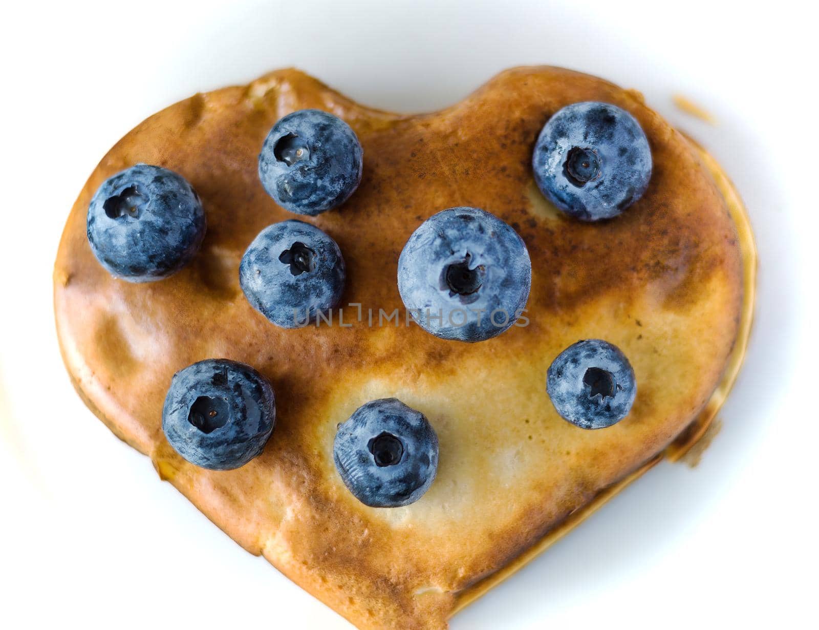 Healthy food concept displaying image of full heart shape pan cake with blueberries fruit on top isolated on white background