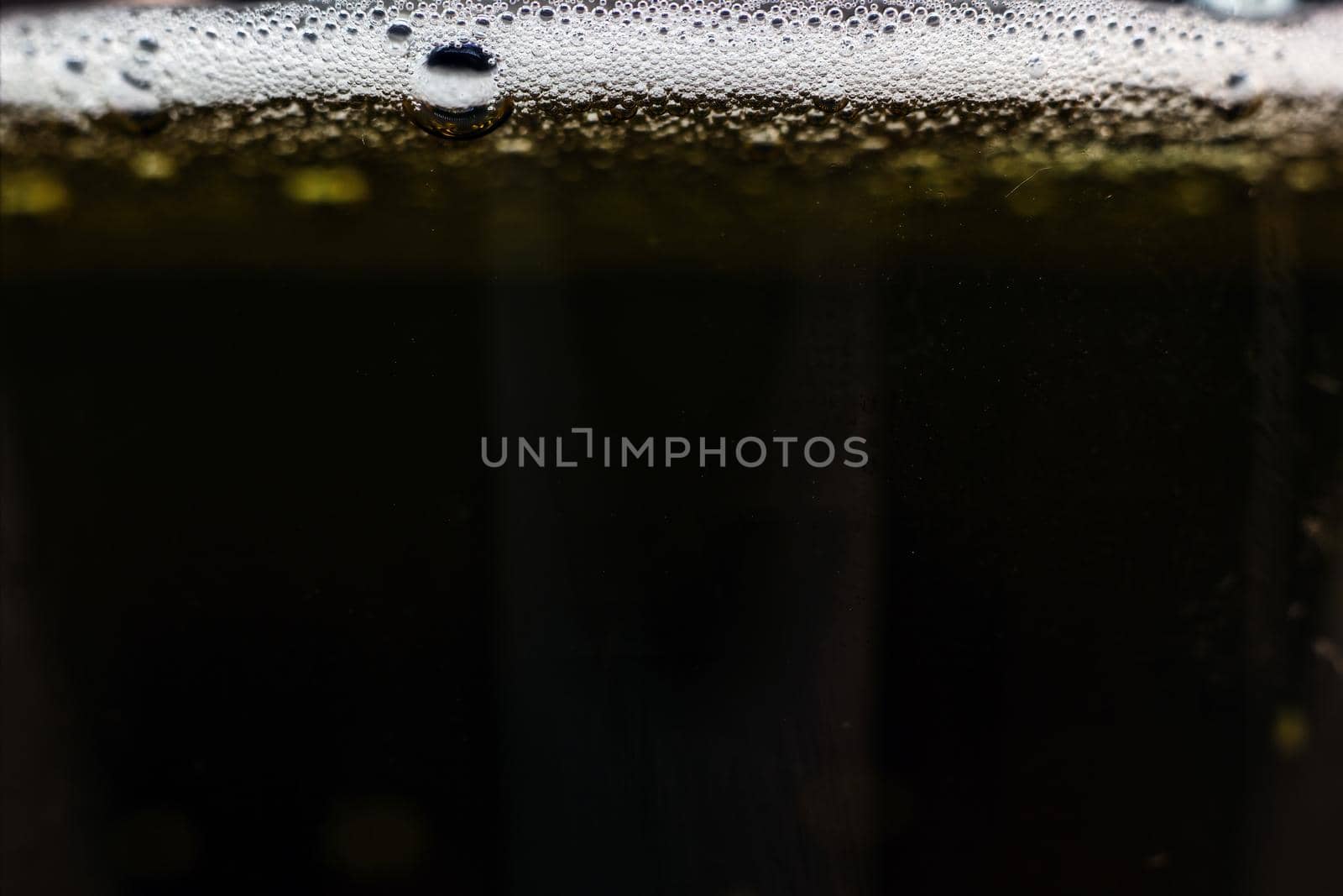 Close-up dark beer with foam and bubbles formed at the edge. by arpanbhatia
