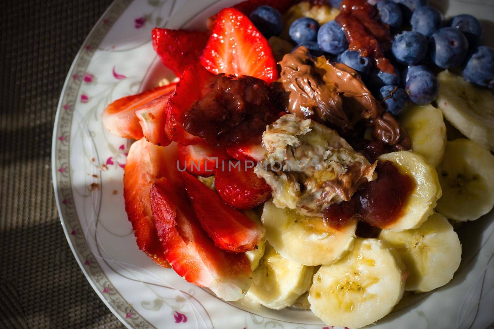 Close up shot of a healthy fruits such as banana, strawberries, blueberries on oats with milk with chocolate and hazelnut cream on top. Healthy morning breakfast concept