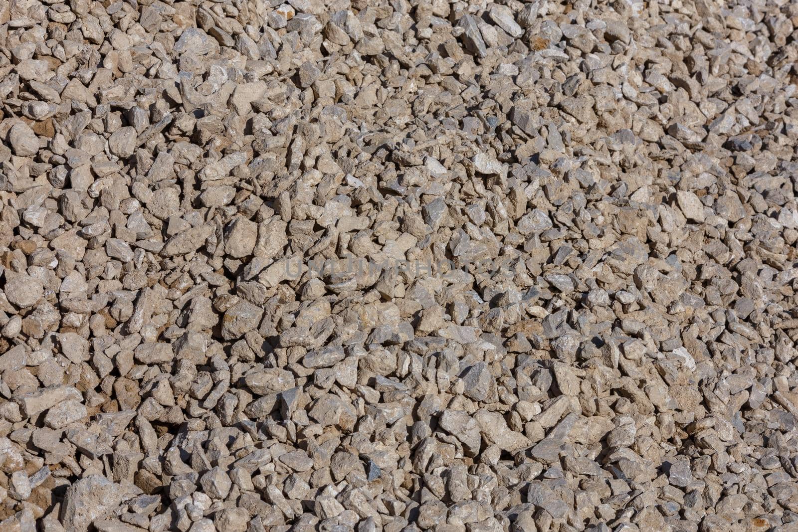 Dirty dry white limestone ballast flat full frame background. Small gray dusty broken macadam stones texture. Viiew from above.