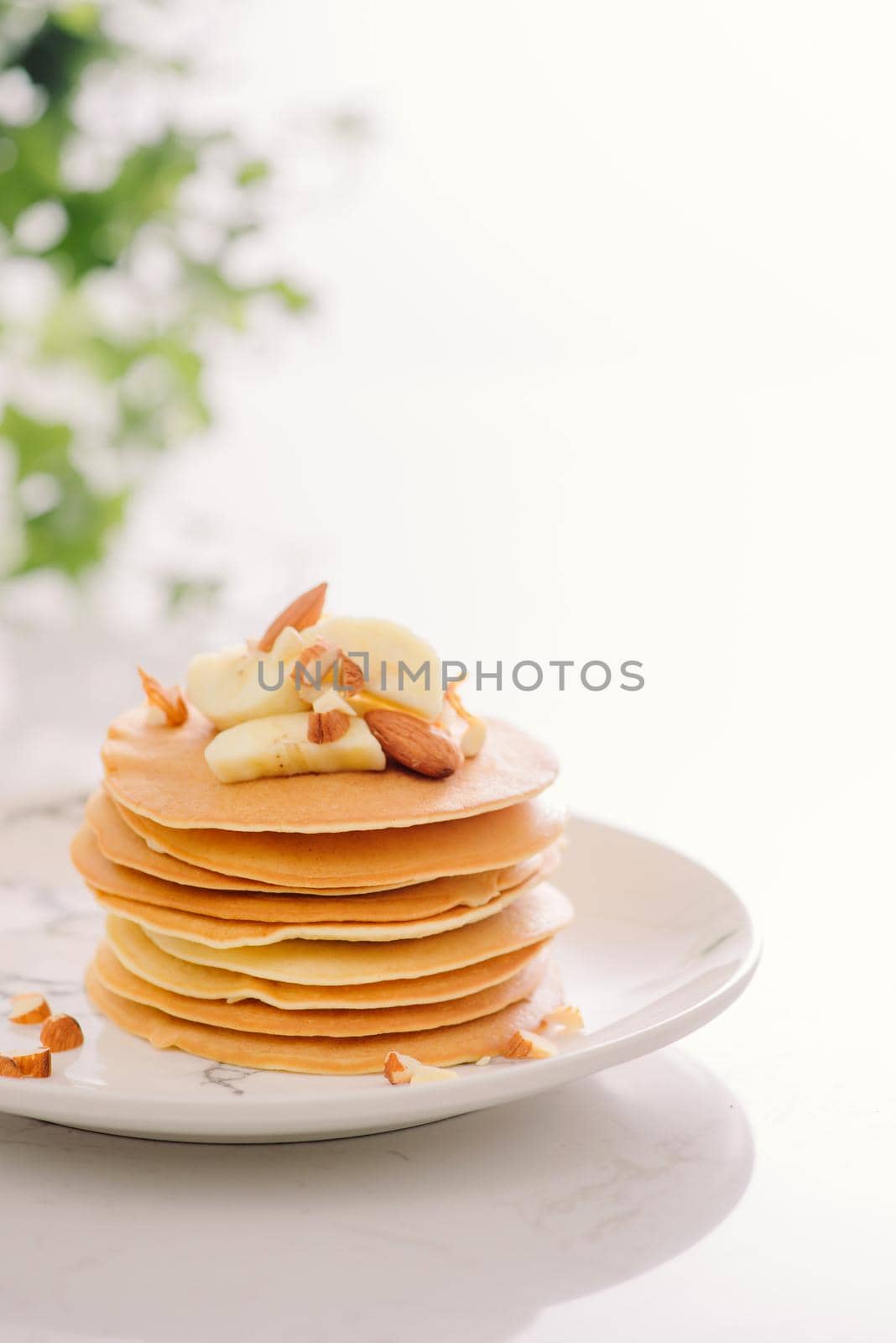 Stack of delicious pancakes with chocolate, honey, nuts and slices of banana on plate on stone background by makidotvn