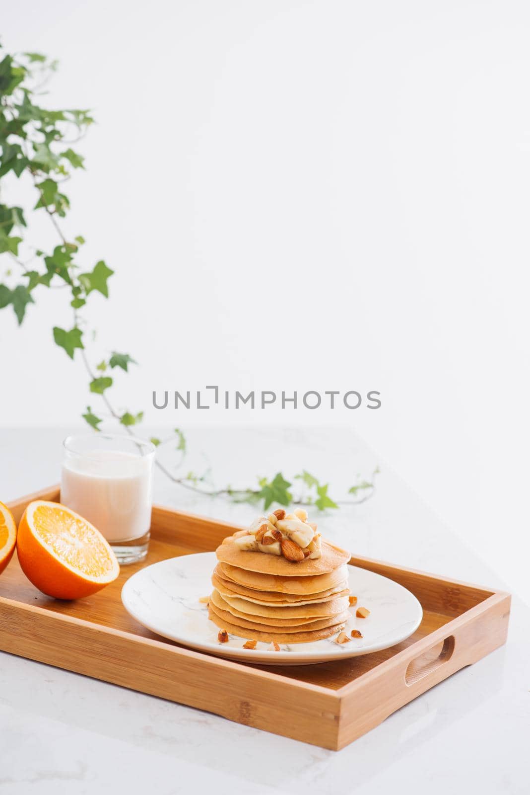 Stack of delicious pancakes with chocolate, honey, nuts and slices of banana on plate and napkin on stone background by makidotvn