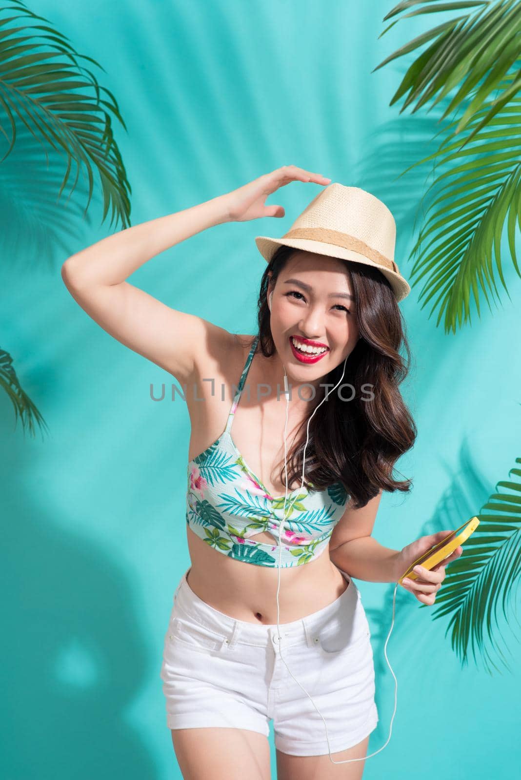 Summer fashion girl standing and smiling over vibrant blue background