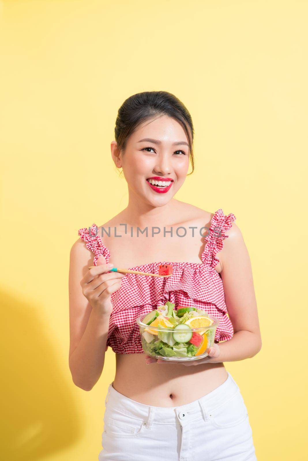 Fashion portrait of young fashionable woman in summer outfit posing with bowl of salad by makidotvn