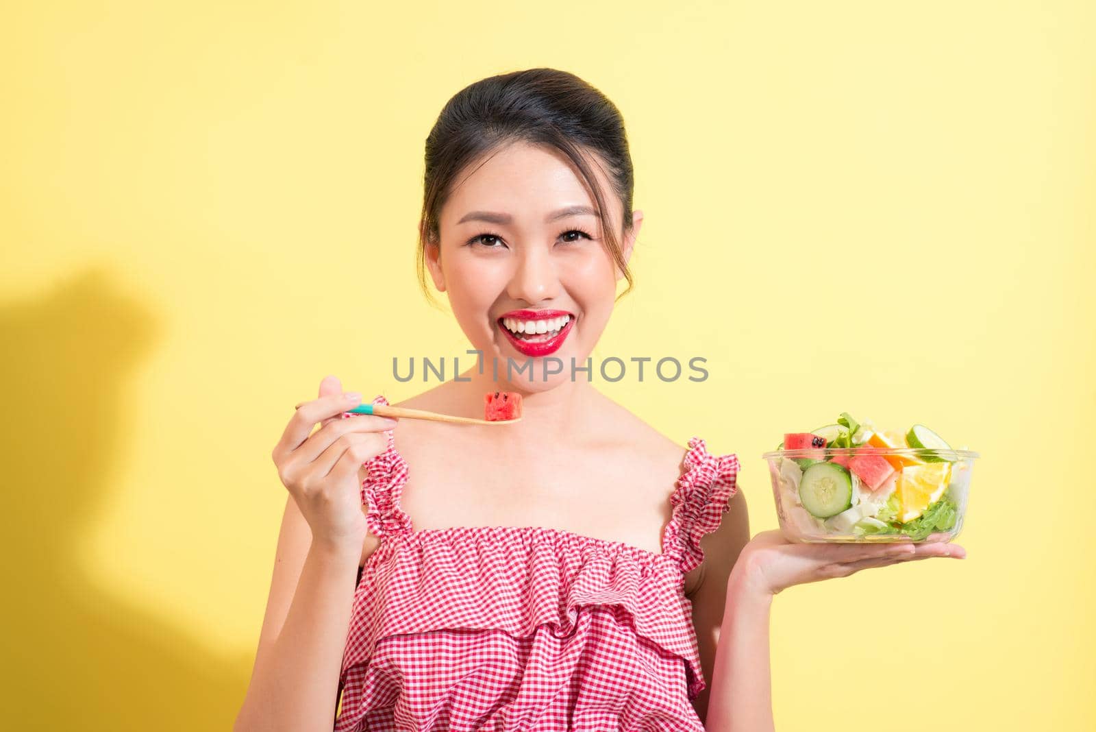 Fashion portrait of young fashionable woman in summer outfit posing with bowl of salad
