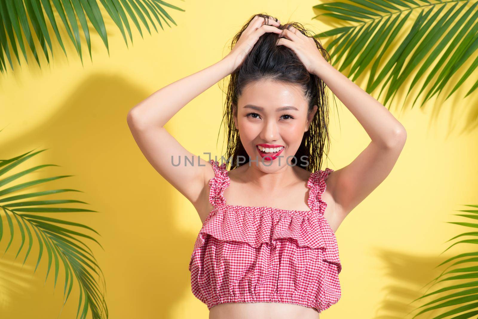 Summer fashion girl standing and smiling over vibrant yellow background