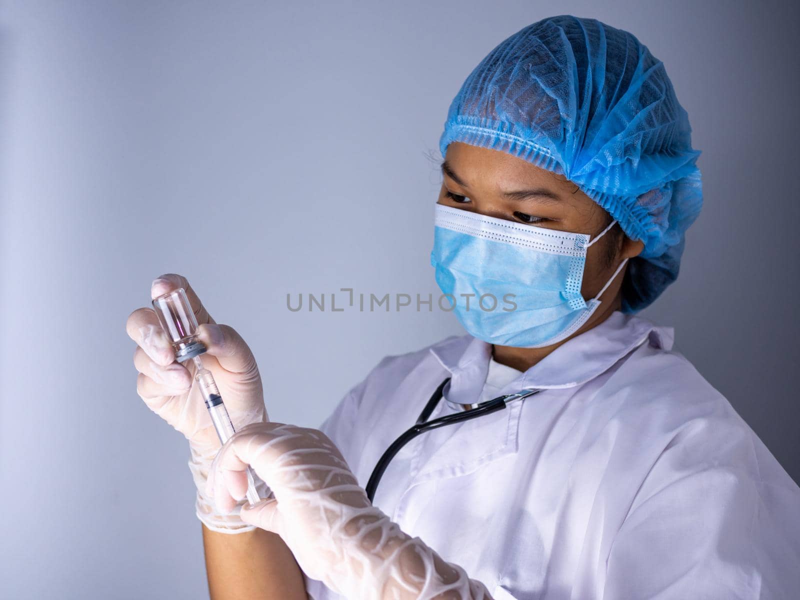 Studio portrait of a female doctor wearing a mask and wearing a hat. In hand was a bottle of vaccine and a sling of syringes. standing on a white background. Studio shot background, COVID-19 concept