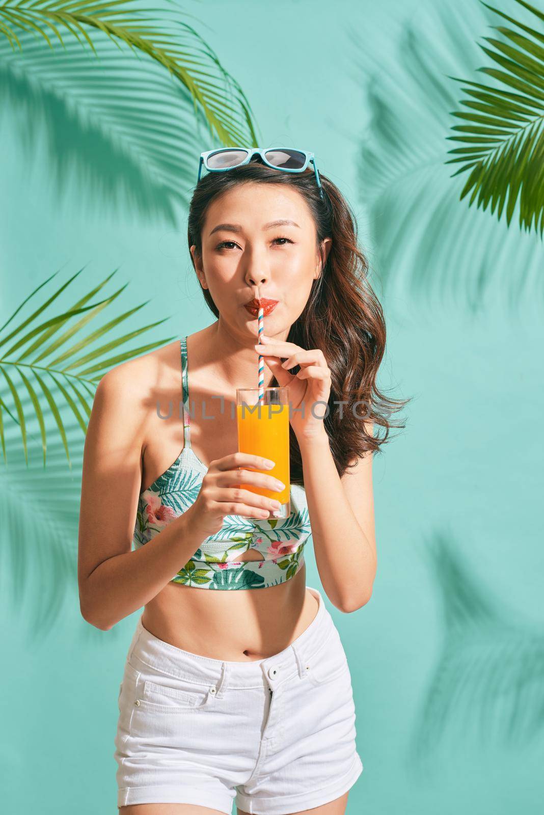 Young sexy asian woman in mini denim shorts drinking tasty juice on summer time by makidotvn