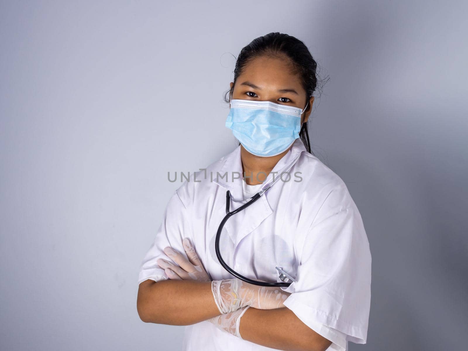 Studio portrait of a female doctor wearing a mask standing on a white background There was a slight light on his face.