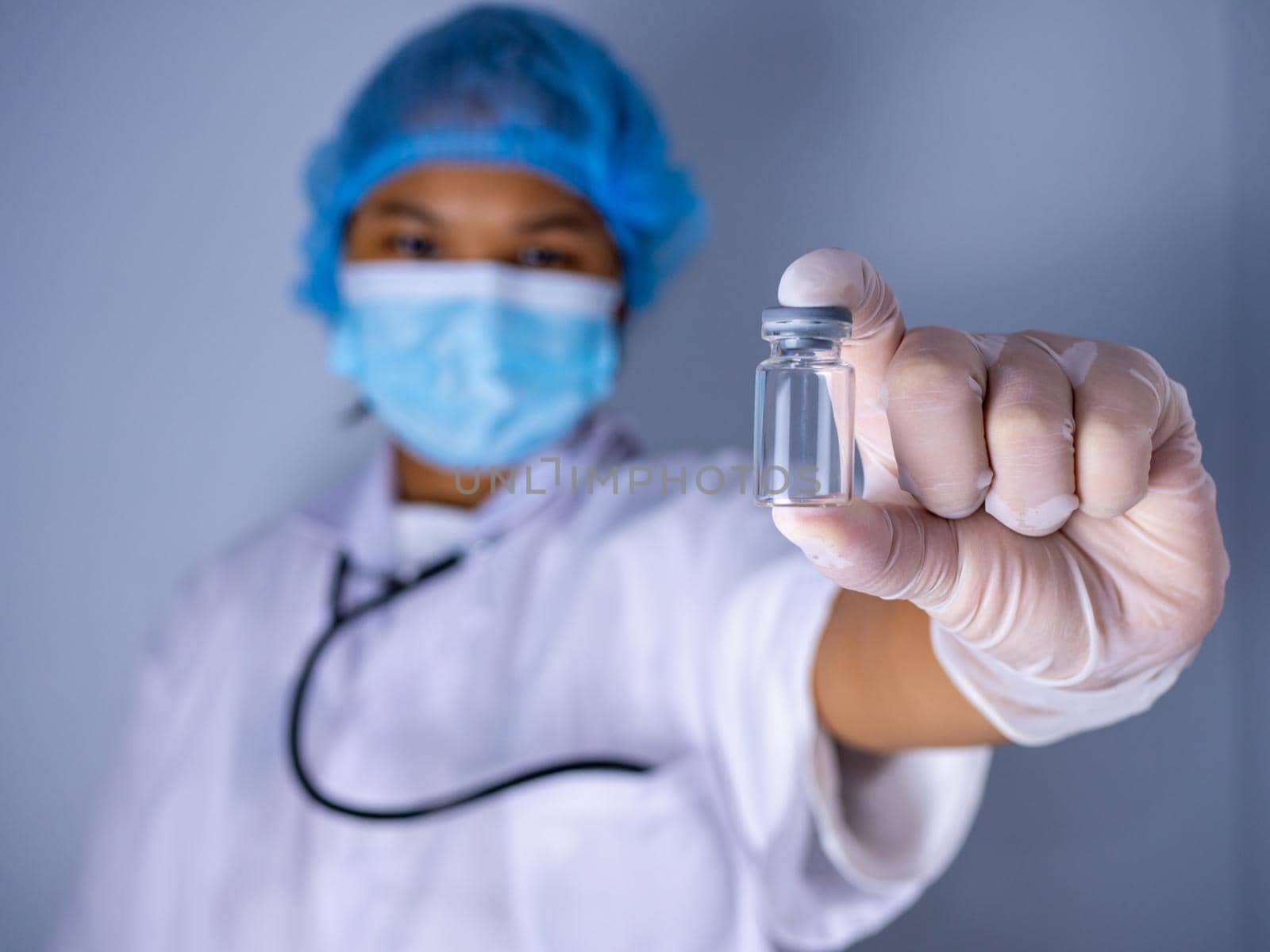 Studio portrait of a female doctor wearing a mask and wearing a hat. in the hand of the vaccine bottle and stretched out his arms in front standing on a white background. studio shot background, COVID-19 concept