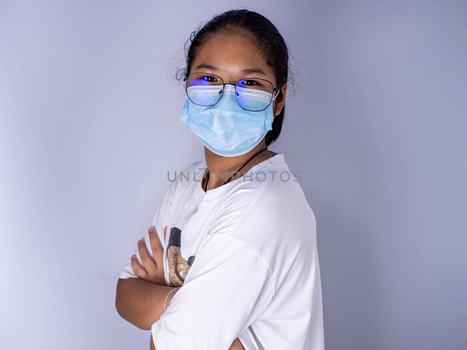 girl wearing a mask and wearing glasses standing with arms crossed on a white background by Unimages2527