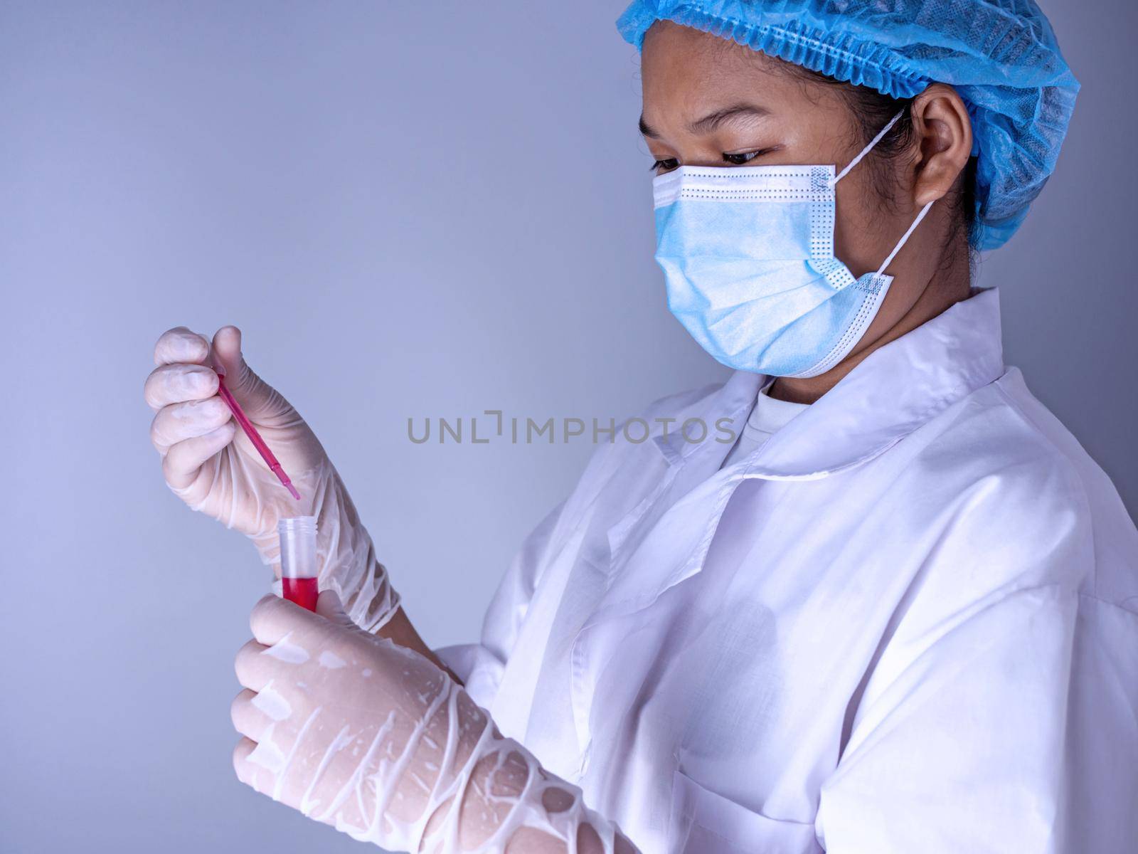 Woman chemist holds flask with red liquid in her hands in chemical laboratory.  Products quality control concept.