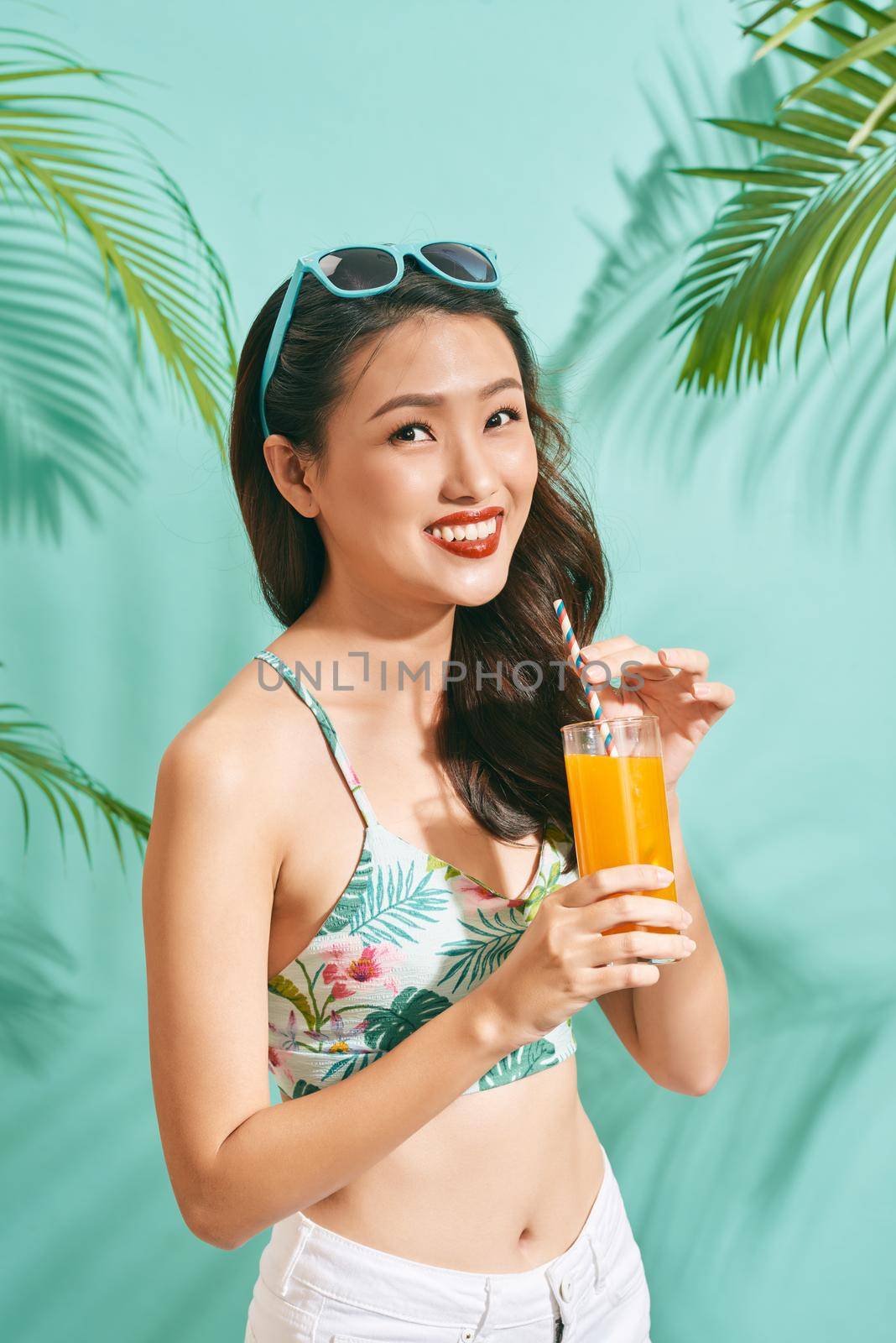 Young sexy asian woman in mini denim shorts drinking tasty juice on summer time