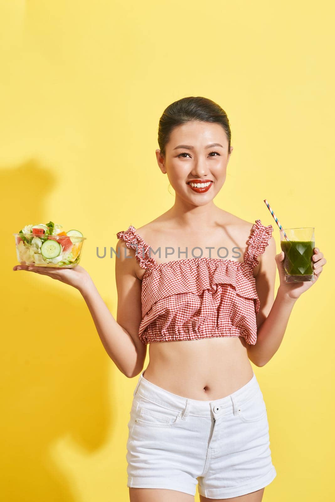 Pretty Asian woman holding salad bowl and green juice
