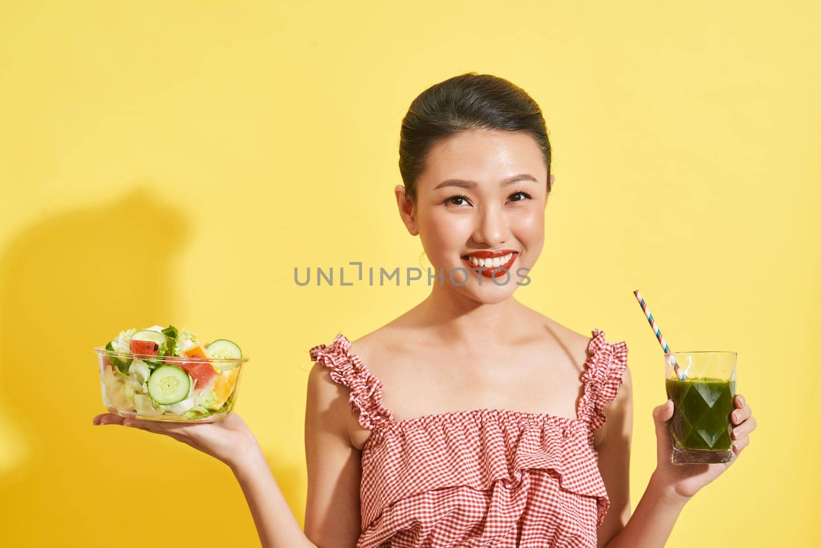 Pretty Asian woman holding salad bowl and green juice