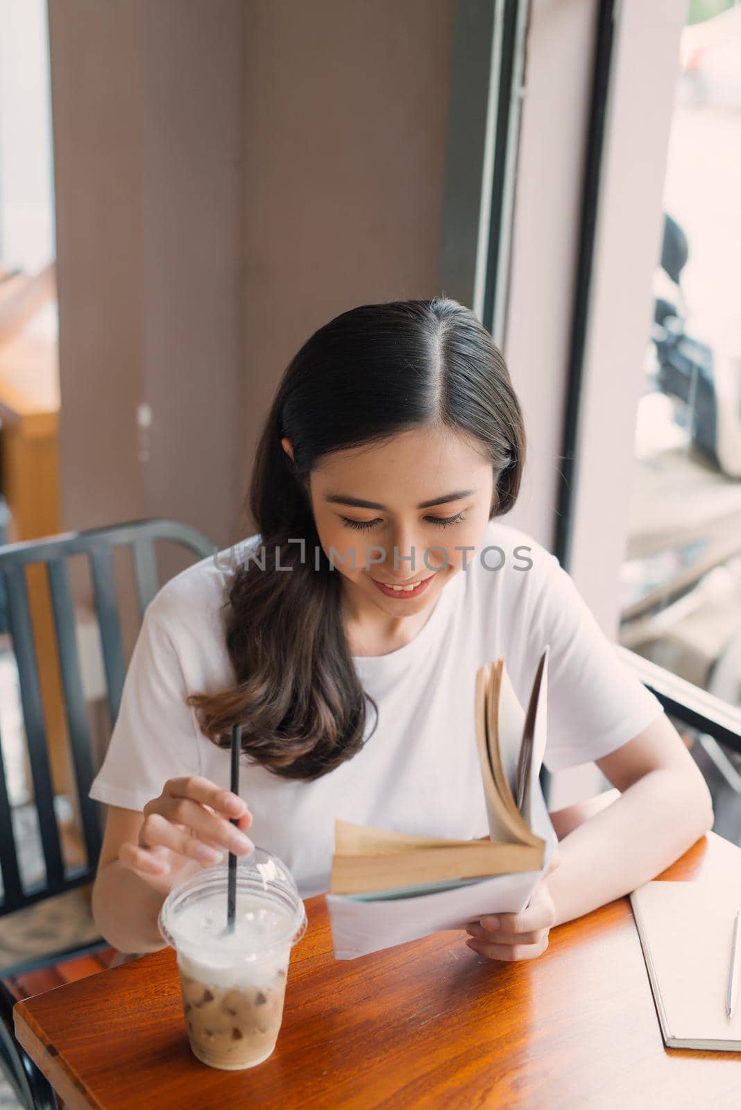 Portrait of Asian woman reading book in coffee shop cafe vintage color tone