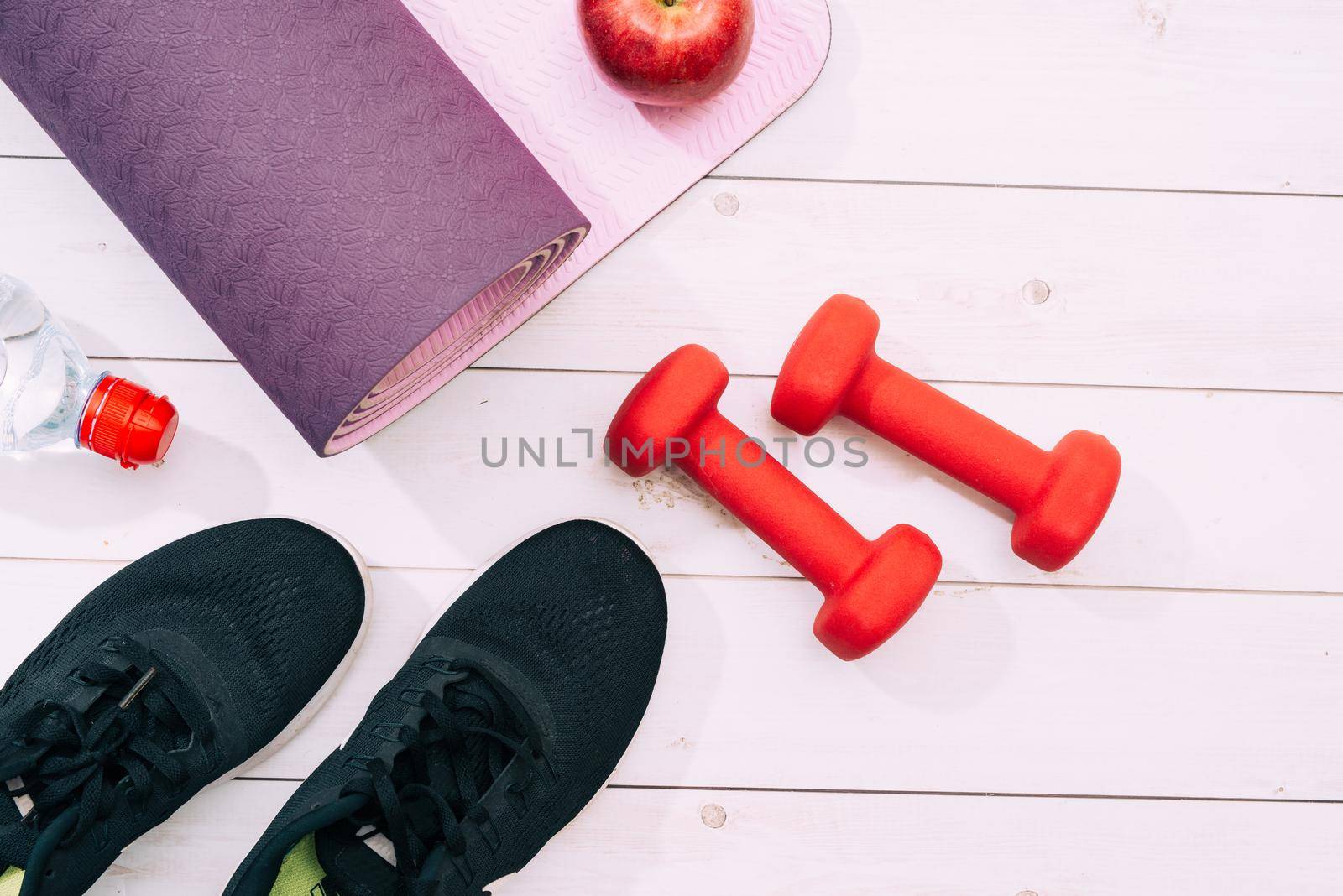Yoga mat, sport shoes, dumbbells and bottle of water on blue background. Concept healthy lifestyle, sport and diet. Sport equipment. Copy space