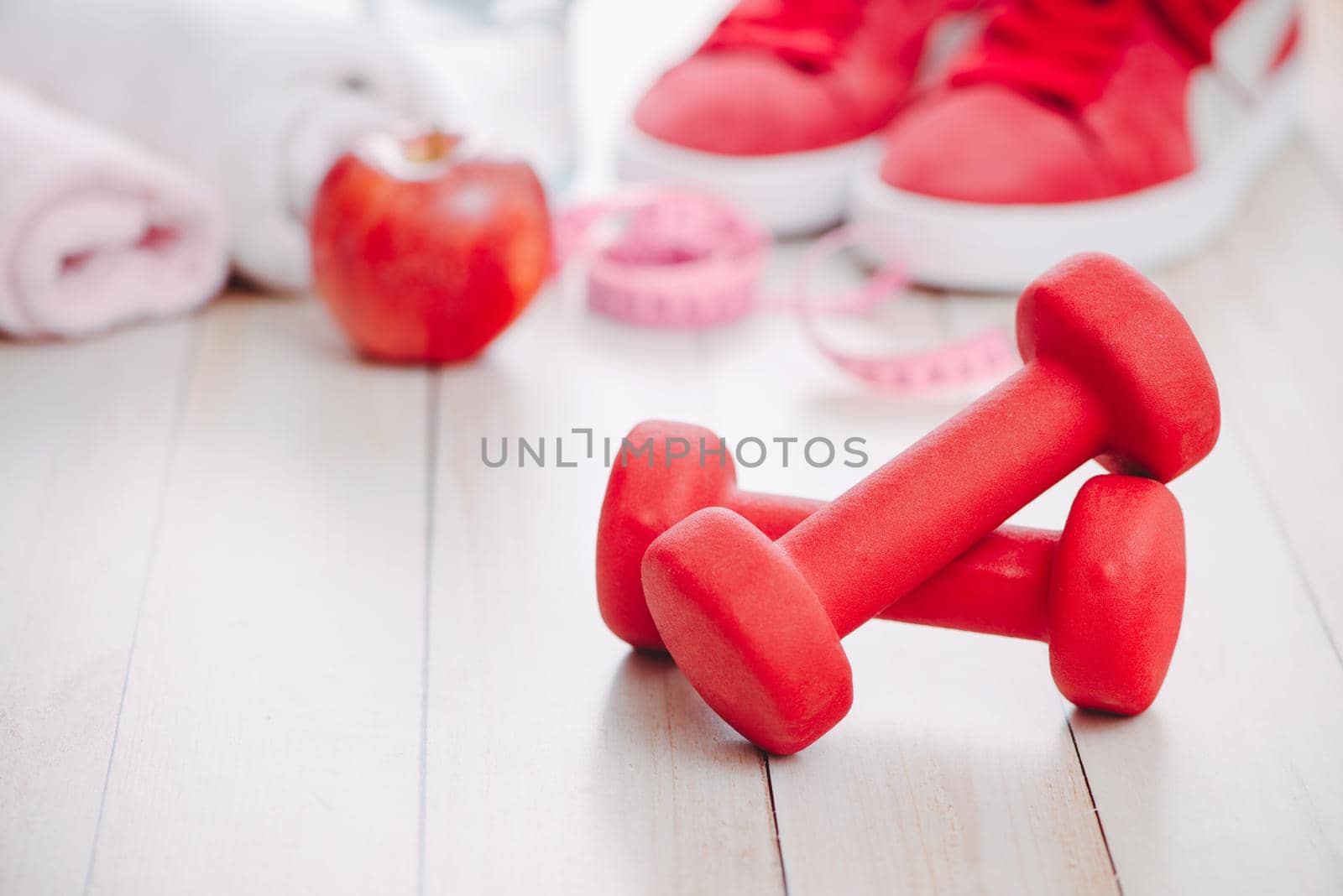 Fitness, healthy and active lifestyles Concept, dumbbells, sport shoes, bottle of waters and apple on wood background. by makidotvn