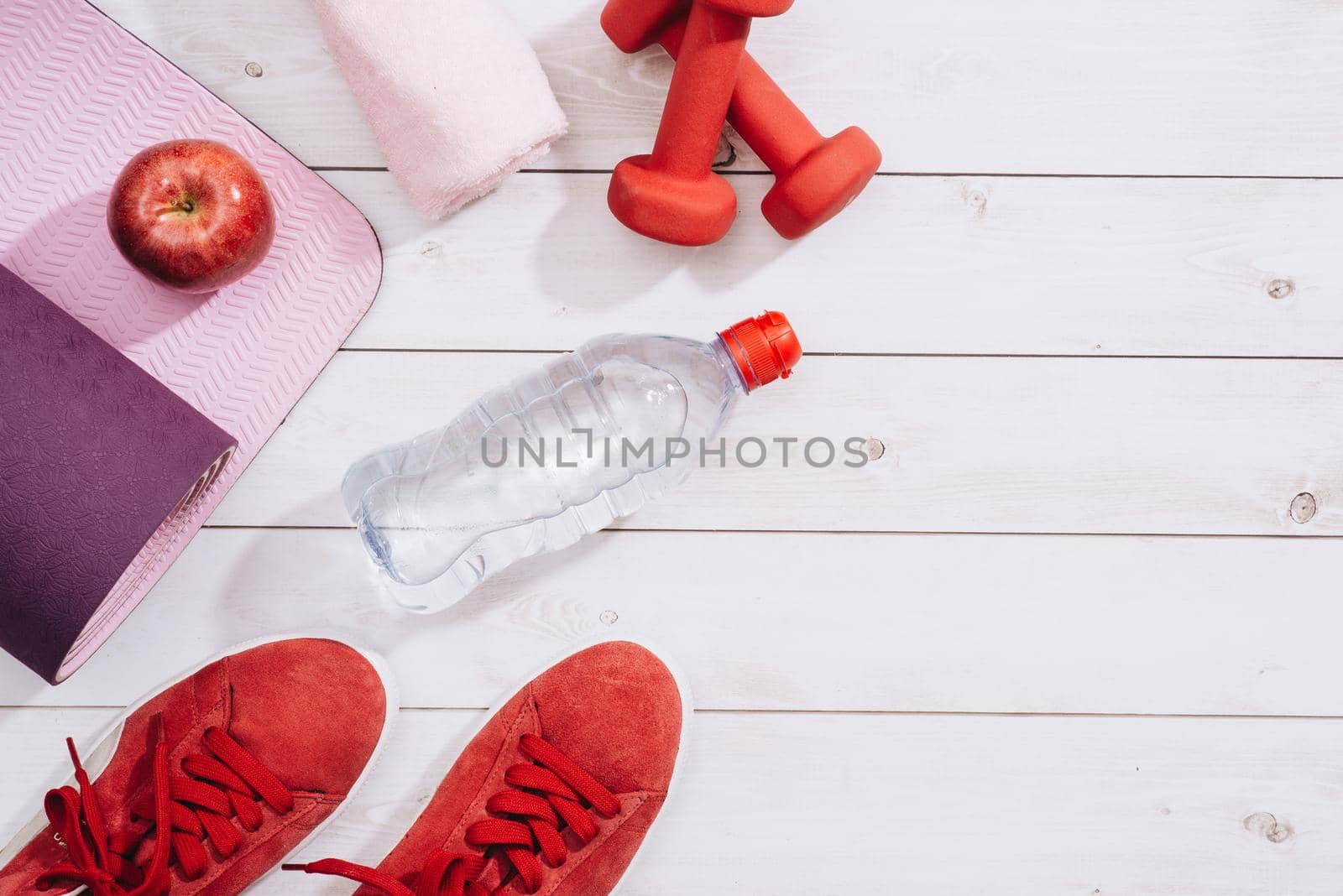 Fitness, healthy and active lifestyles Concept, dumbbells, sport shoes, bottle of waters and apple on wood background - Image
