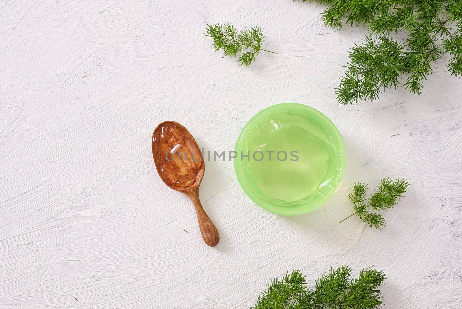 spa setting with cosmetic cream, gel, bath salt and fern leaves on white wooden table background by makidotvn
