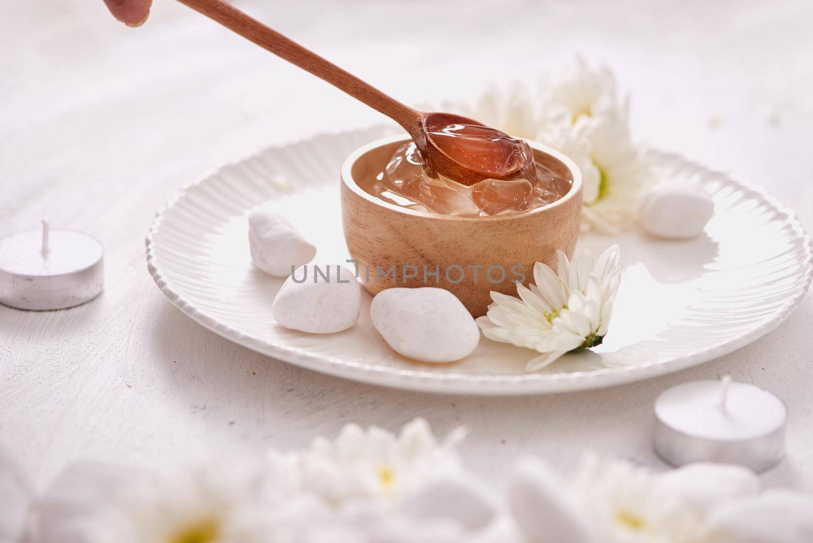 Aloe vera gel on a bowl, with chrysanthemum and candle in stone table