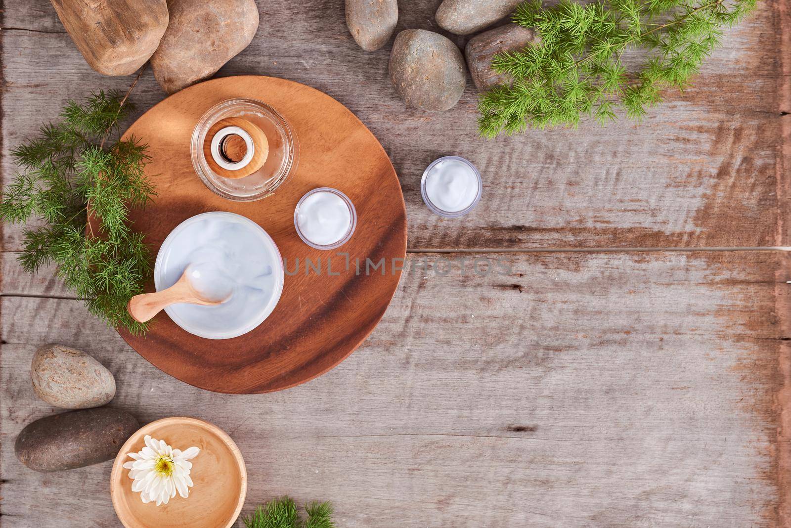 cosmetic cream and fresh  leaves on wooden table background by makidotvn