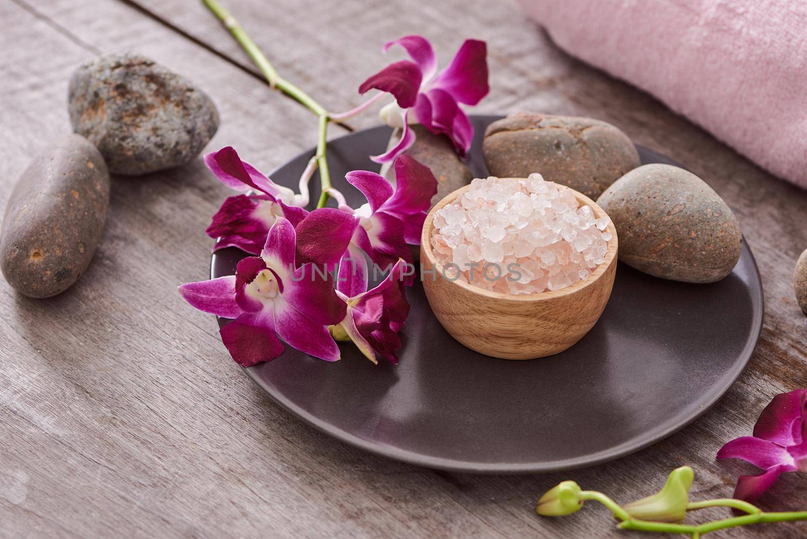 bath salt at bamboo bowl and orchids flowers on dark wood by makidotvn